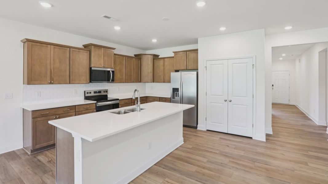 Pendleton home plan open concept kitchen with large island, tile backsplash and abundant cabinetry
