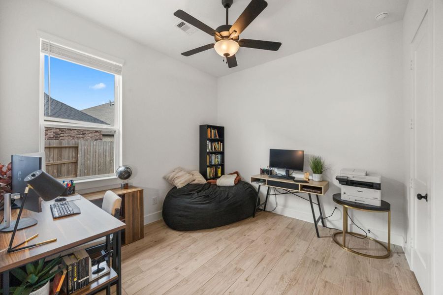 Wood-look tile flooring, a ceiling fan, and a large window make this space ideal for a home office, playroom, or additional living area.