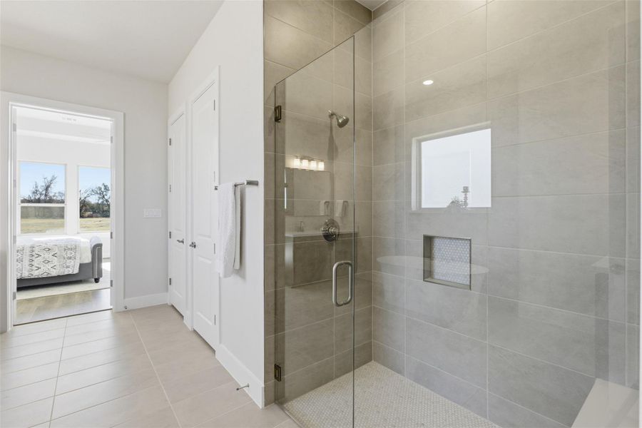 Ensuite bathroom with a shower stall, a closet, and light tile patterned floors
