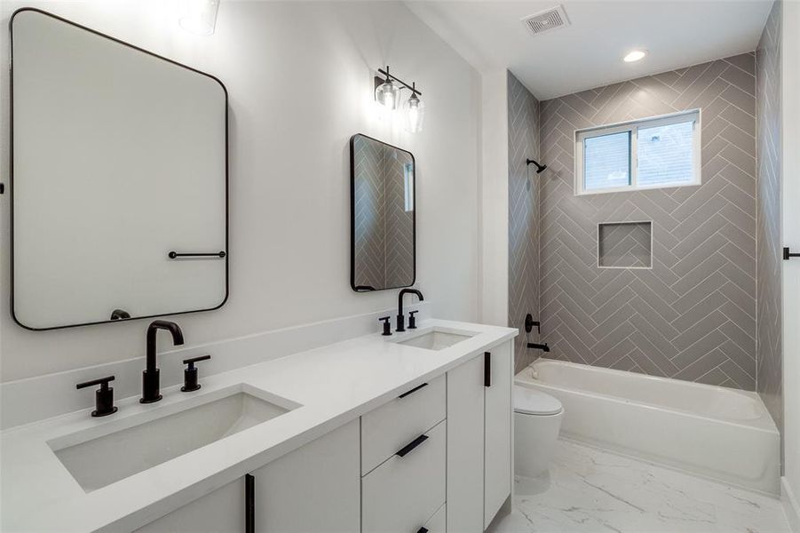 Full bathroom with tiled shower / bath, vanity, and toilet