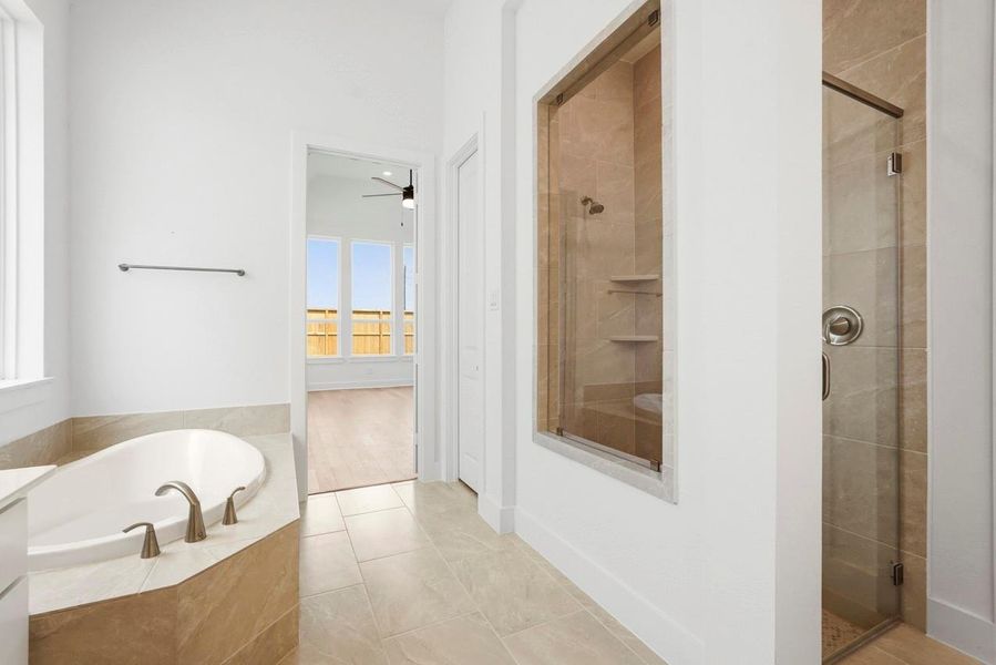 Primary has large walk-in shower with beautiful tile detail.