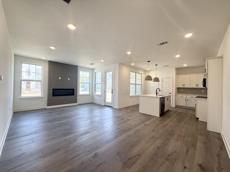 Unfurnished living room with dark wood-style flooring, recessed lighting, and a large fireplace