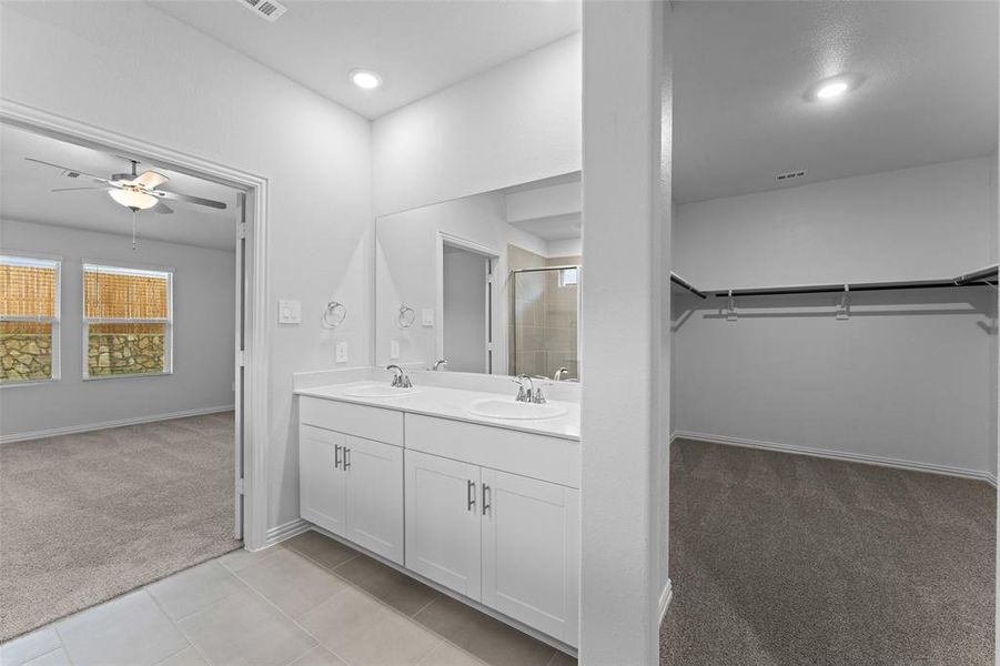 Full bathroom with a shower stall, a walk in closet, double vanity, ceiling fan, and recessed lighting Full bathroom with a shower stall, a walk in closet, double vanity, ceiling fan, and recessed lighting