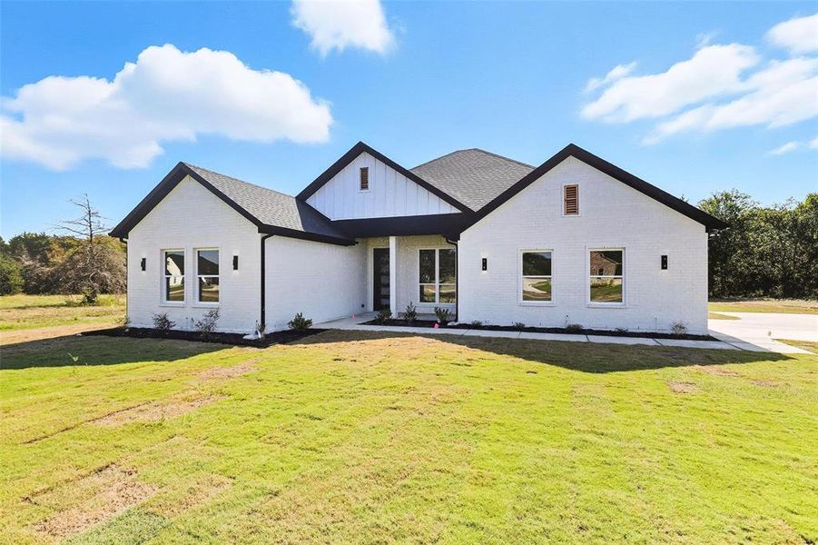 Modern farmhouse with brick siding, a front lawn, and board and batten siding Modern farmhouse with brick siding, a front lawn, and board and batten siding