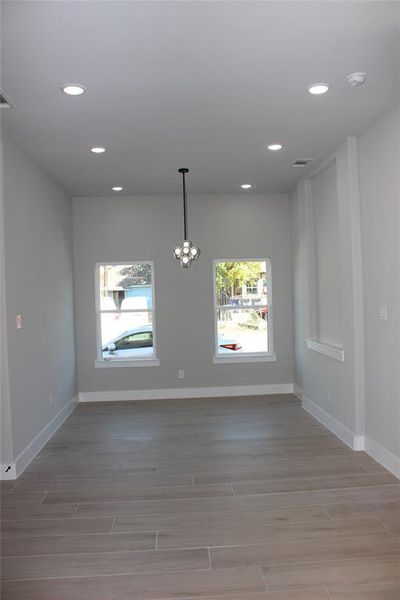 Empty room with a notable chandelier and hardwood / wood-style flooring