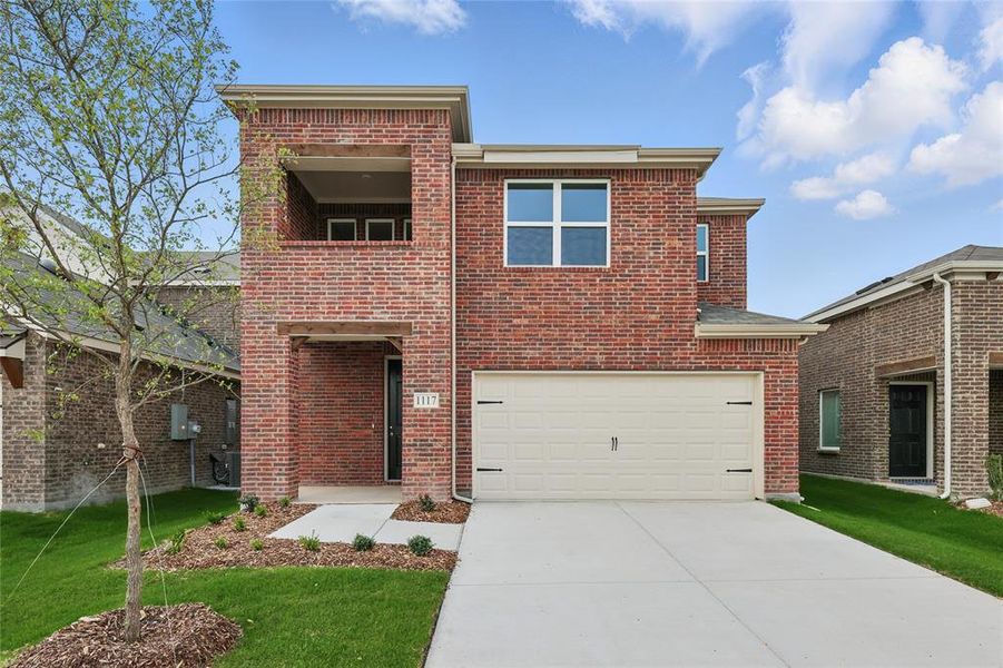 Traditional-style house with brick siding, concrete driveway, a balcony, and a front yard