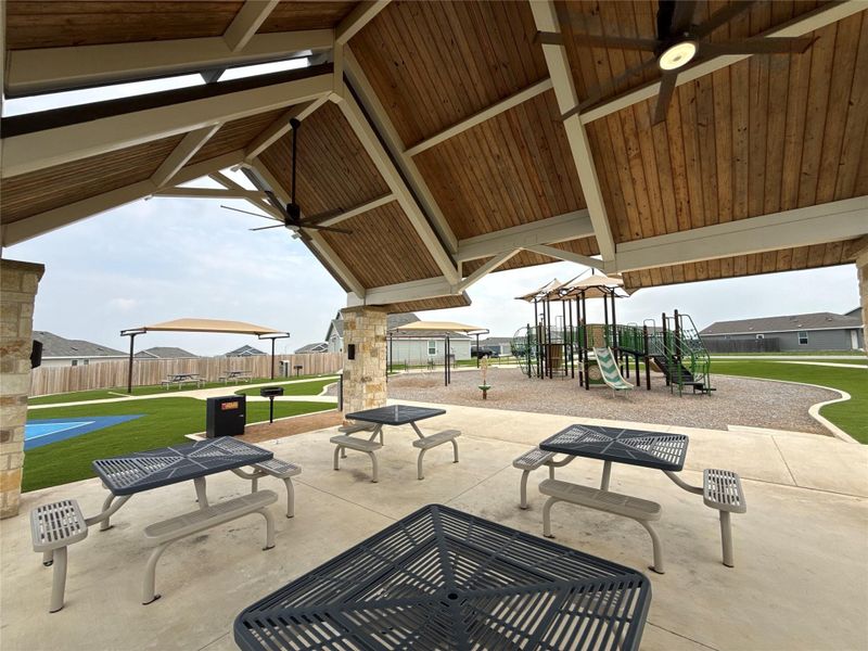 Covered outdoor pavilion with wood-finish ceiling, integrated ceiling fans, and stone-clad pillars