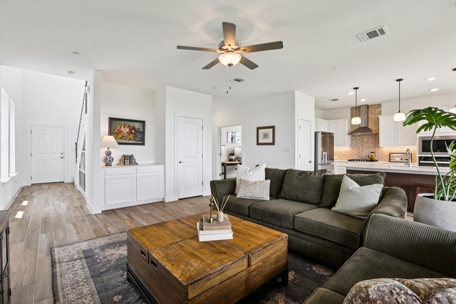 The property features an open-concept living area with a ceiling fan, light-toned flooring, and white walls