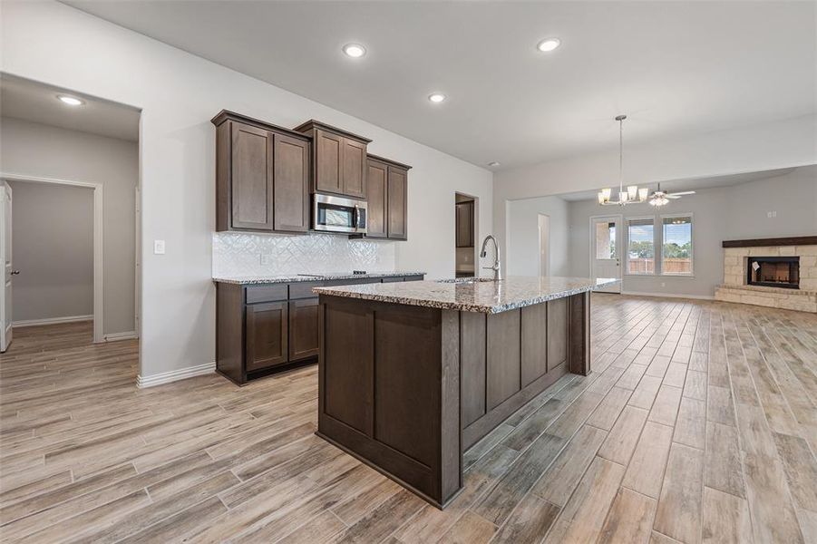 Kitchen featuring light stone counters, tasteful backsplash, recessed lighting, decorative light fixtures, and dark brown cabinetry Kitchen featuring light stone counters, tasteful backsplash, recessed lighting, decorative light fixtures, and dark brown cabinetry
