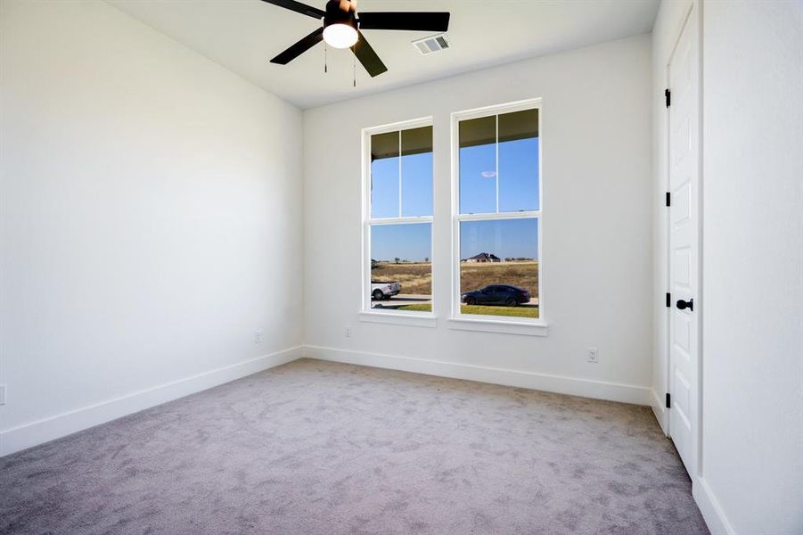 Carpeted empty room featuring ceiling fan