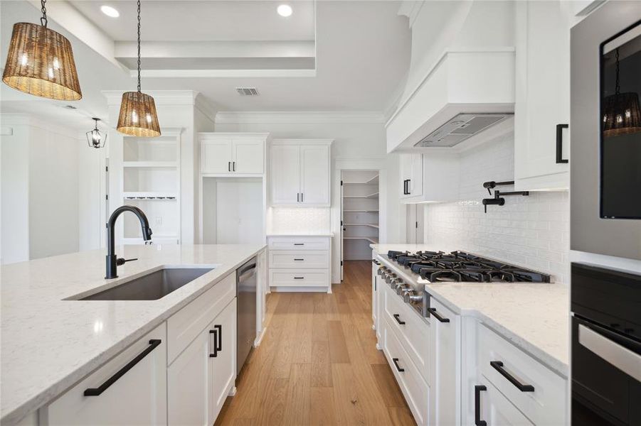 Kitchen featuring light stone countertops, custom exhaust hood, stainless steel appliances, sink, and white cabinets