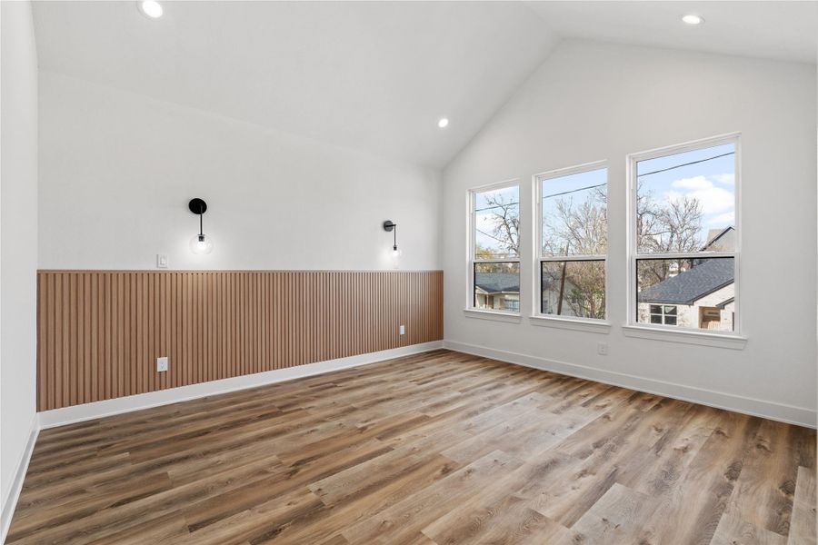 Spacious primary bedroom with a modern accent wall, vaulted ceiling, and tons of natural light.