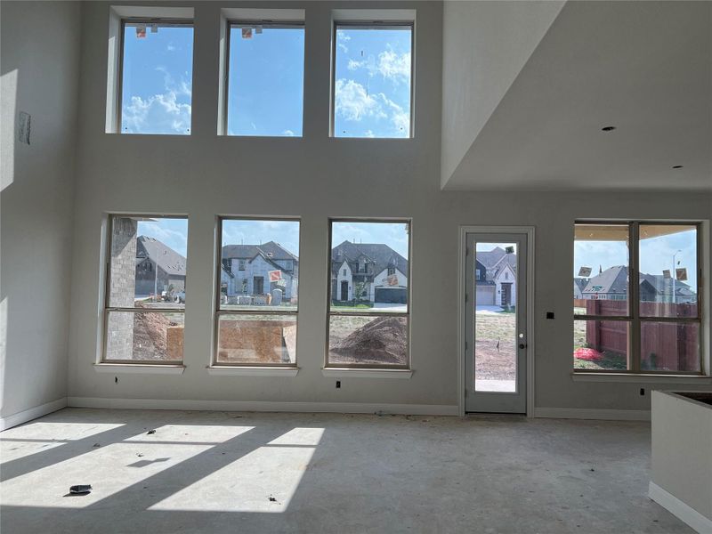 Unfurnished living room with baseboards and a towering ceiling Unfurnished living room with baseboards and a towering ceiling