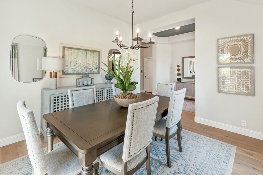Dining room with dark wood table, upholstered chairs, chandelier, and buffet sideboard on hardwood floors
