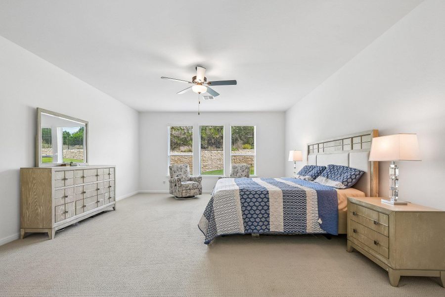 A well-lit bedroom with comfortable carpeting, offering views of the natural landscape through multiple windows.
