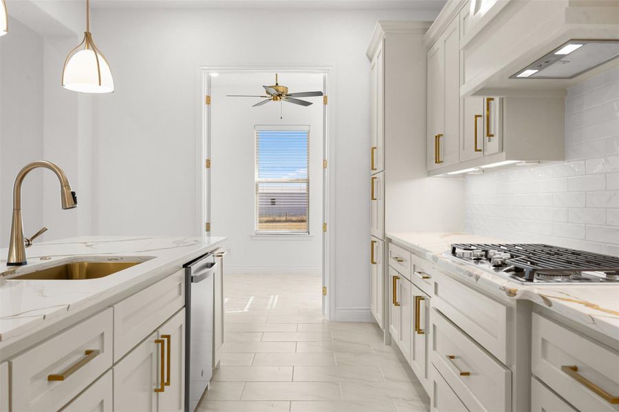 Kitchen featuring white cabinets, light stone countertops, hanging light fixtures, and stainless steel appliances