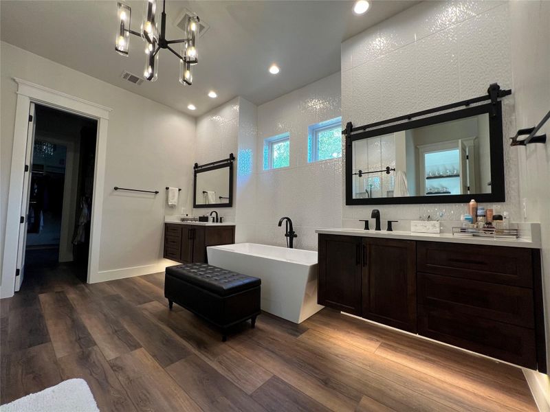 Full bath with a freestanding bath, two vanities, recessed lighting, and a walk in closet his and hers closets Full bath with a freestanding bath, two vanities, recessed lighting, and a walk in closet his and hers closets