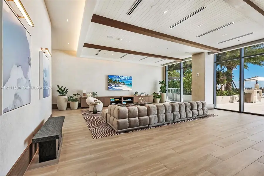 Expansive room featuring a wood-plank ceiling with decorative beams, floor-to-ceiling glass windows, recessed lighting, and large-format wood-finish flooring Expansive room featuring a wood-plank ceiling with decorative beams, floor-to-ceiling glass windows, recessed lighting, and large-format wood-finish flooring
