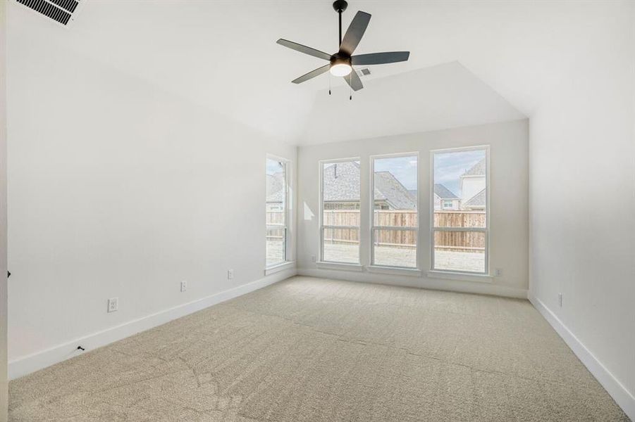 Spare room with carpet, a ceiling fan, and vaulted ceiling
