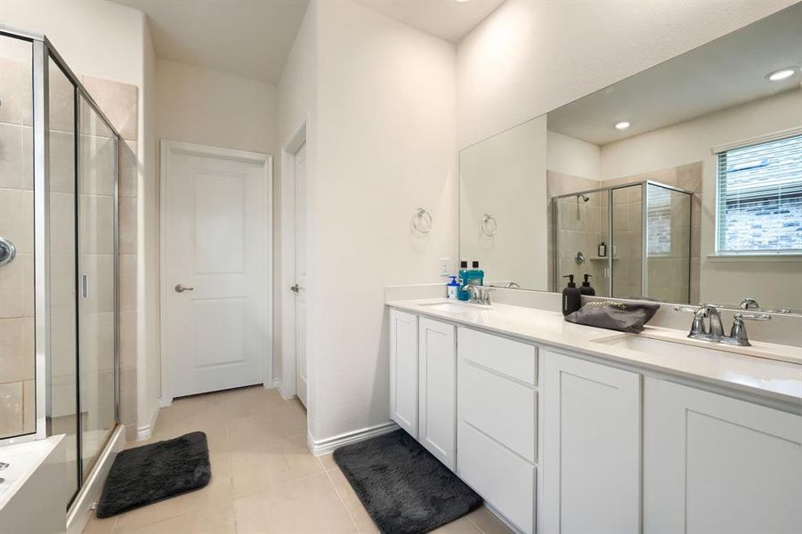 Full bathroom featuring double vanity, a shower stall, and light tile patterned flooring Full bathroom featuring double vanity, a shower stall, and light tile patterned flooring