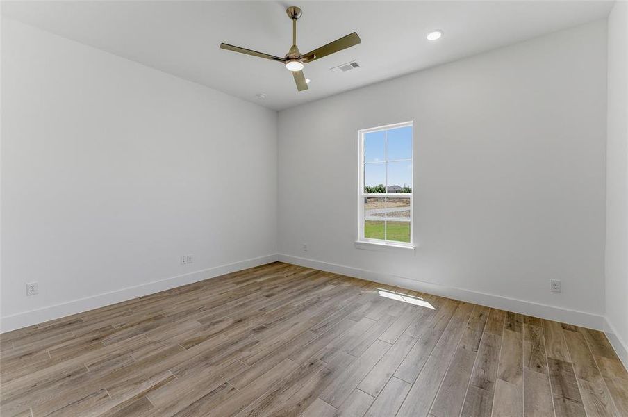 Bright interior space featuring a window, wood-finish flooring, a ceiling fan, recessed lighting, and white baseboards