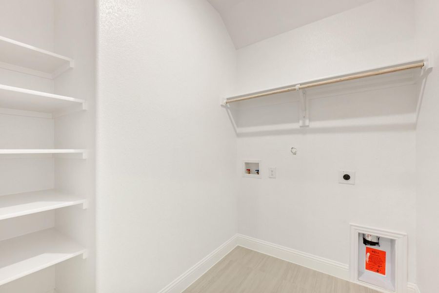 Laundry room with built-in shelves, hanging rod, washer and dryer hookups, and wood-look floors