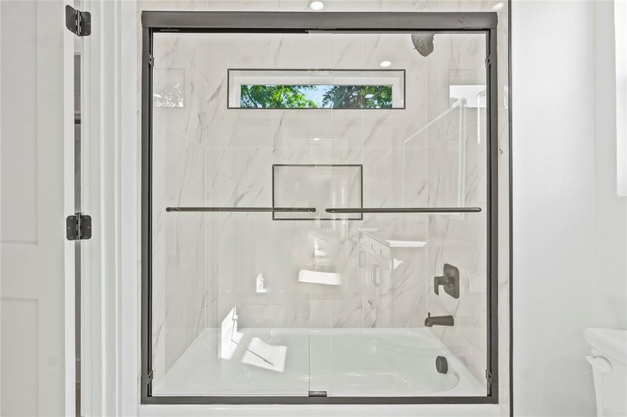 Bathroom featuring enclosed tub / shower combo and toilet