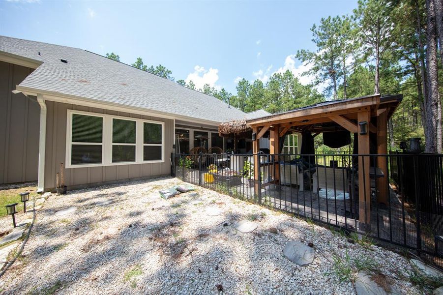 This home features a charming backyard with a covered patio area, perfect for outdoor entertaining. The space includes a fenced section and is surrounded by trees, offering privacy and a natural setting.