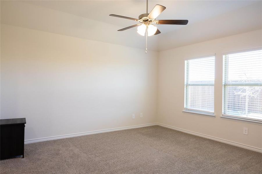 Carpeted empty room with baseboards and a ceiling fan Carpeted empty room with baseboards and a ceiling fan
