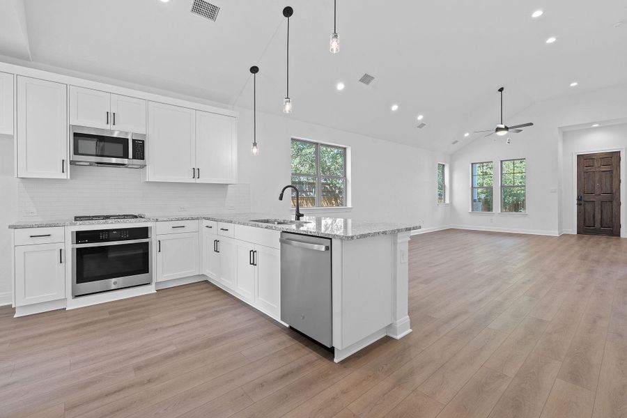 Kitchen featuring appliances with stainless steel finishes, white cabinets, backsplash, recessed lighting, and vaulted ceiling