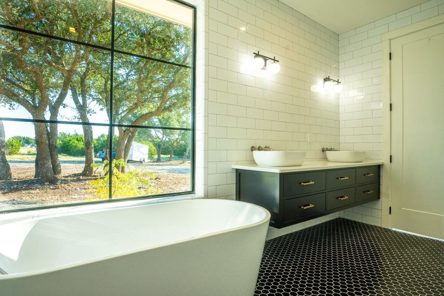 Bathroom with tile walls, double vanity, a freestanding tub, and tile patterned floors