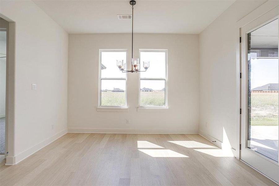 Unfurnished dining area with a chandelier and light wood-type flooring