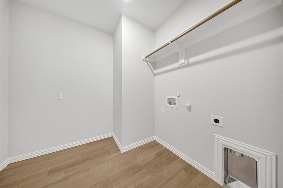 Laundry area featuring hookup for a gas dryer, hookup for an electric dryer, light wood-style flooring, and hookup for a washing machine Laundry area featuring hookup for a gas dryer, hookup for an electric dryer, light wood-style flooring, and hookup for a washing machine