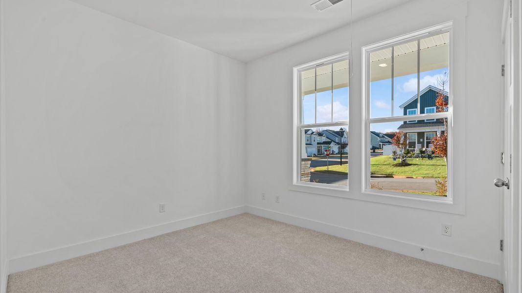 Elegant bedroom retreat featuring soft carpet and oversized windows that create a bright, welcoming space