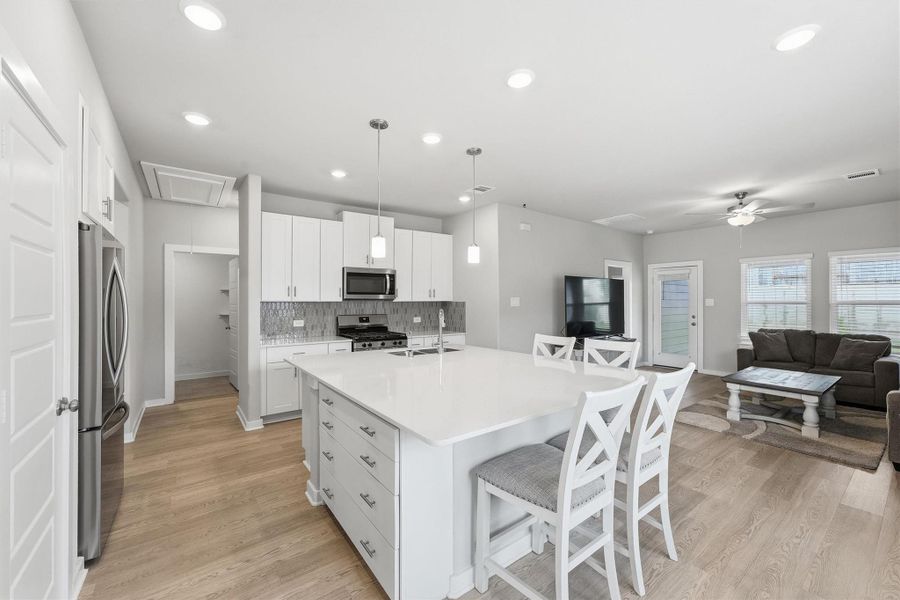 Open Kitchen with bright white and greys. The giant Island with sink was enhanced by the seller who added the extra kitchen storage with 4 drawers. The seller also added cabinets over the Refrigerator taking empty space and making it useful. Stainless steel appliances compliment the neutral tones in the space. Open Kitchen with bright white and greys. The giant Island with sink was enhanced by the seller who added the extra kitchen storage with 4 drawers. The seller also added cabinets over the Refrigerator taking empty space and making it useful. Stainless steel appliances compliment the neutral tones in the space.