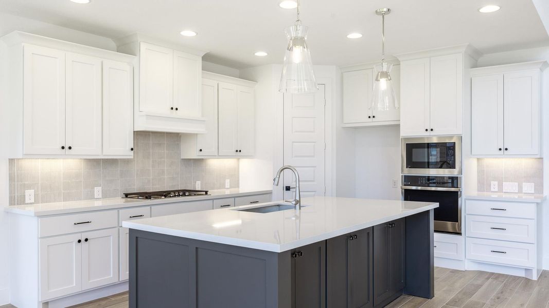 Kitchen with tasteful backsplash, white cabinetry, recessed lighting, a center island with sink, and light wood-type flooring