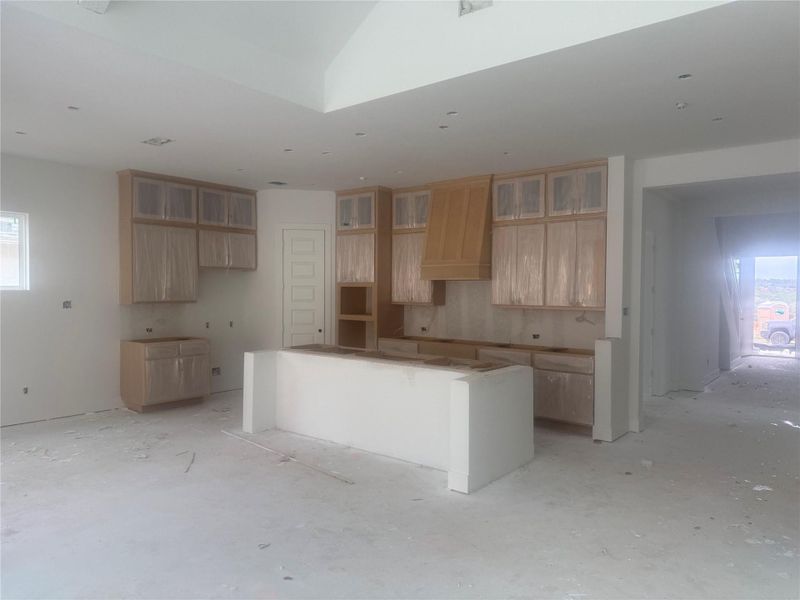 Kitchen with plenty of natural light, a kitchen island, light brown cabinets, and custom exhaust hood