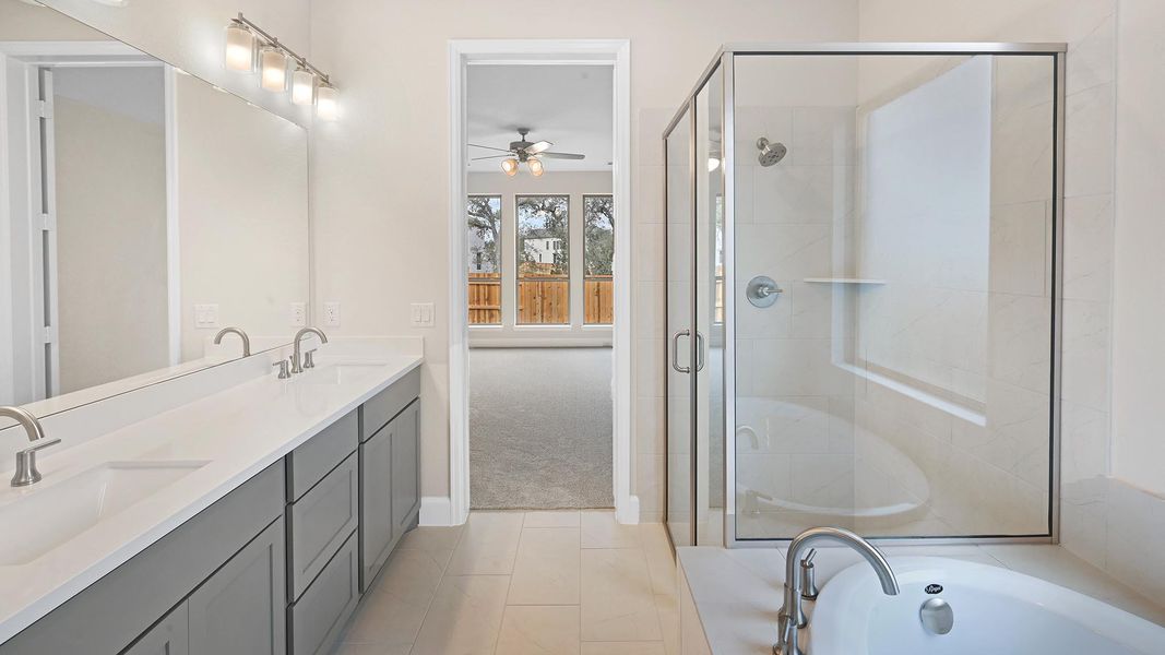 Full bathroom with double vanity, a stall shower, light tile patterned flooring, a bath, and light carpet