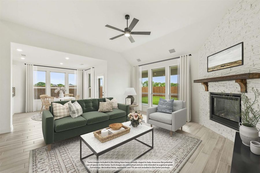 Living room with white stone fireplace, ceiling fan, hardwood floors, and large windows overlooking backyard Living room with white stone fireplace, ceiling fan, hardwood floors, and large windows overlooking backyard