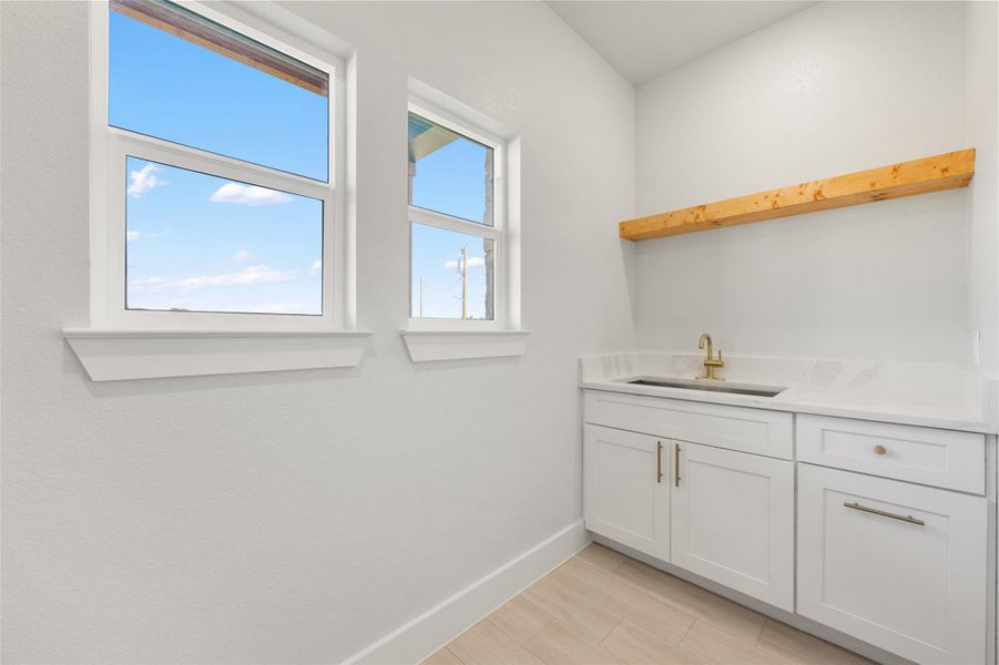 Bar area with white cabinetry, open shelves, light stone countertops, and light wood-style flooring