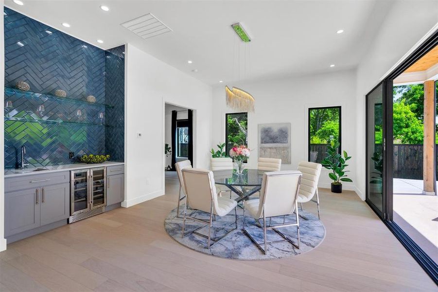 Dining space featuring wine cooler, light wood-type flooring, wet bar, and recessed lighting