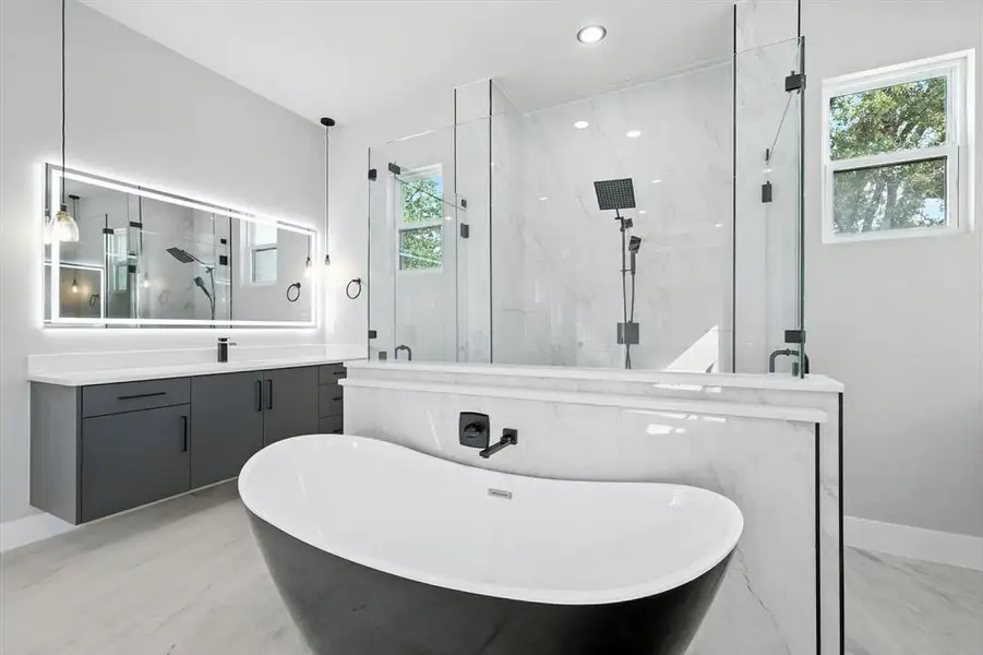 Full bathroom featuring a soaking tub, vanity, a marble finish shower, light marble finish flooring, and recessed lighting Full bathroom featuring a soaking tub, vanity, a marble finish shower, light marble finish flooring, and recessed lighting