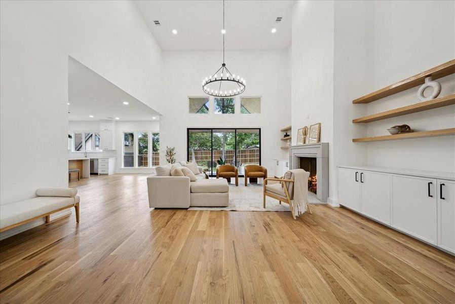 Living room featuring a high ceiling, hardwood flooring, and a notable chandelier