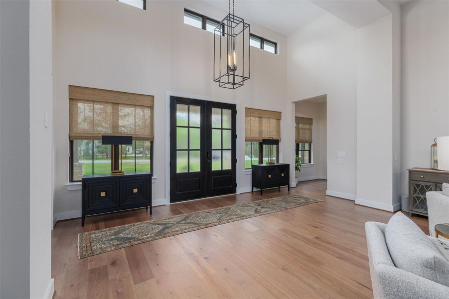 The double doors open to a unique entrance foyer which perfectly captures the WOW factor of the home's luxurious interior at first glance.  Wide 7" plank Pecan Engineered wood flooring throughout the open plan living space.  Dramatic high ceilings and statement chandelier lighting provide focus to the modern contemporary design elements that flow throughout the home.