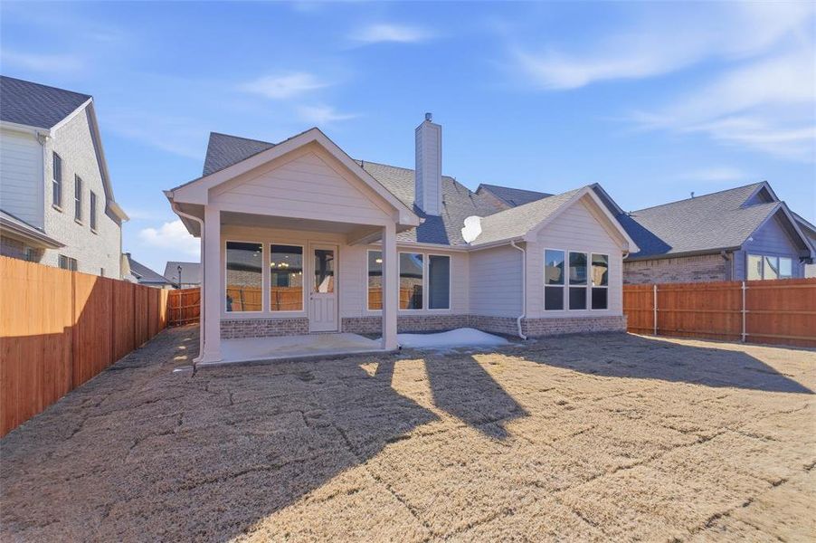 Back of house featuring a chimney, a patio, a fenced backyard, brick siding, and roof with shingles
