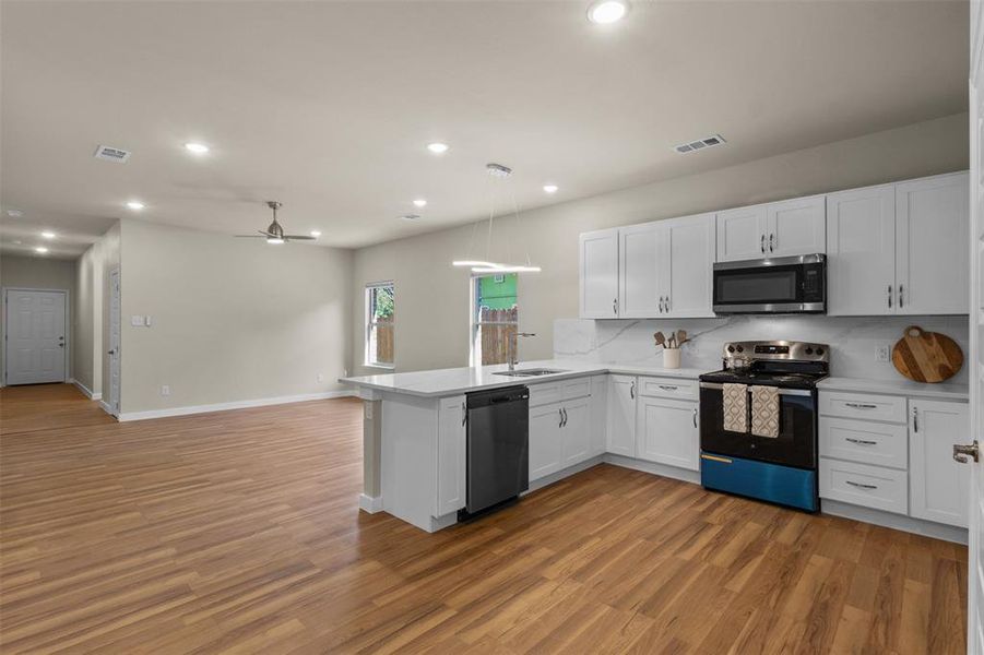 Kitchen with appliances with stainless steel finishes, white cabinets, ceiling fan, recessed lighting, and open floor plan Kitchen with appliances with stainless steel finishes, white cabinets, ceiling fan, recessed lighting, and open floor plan