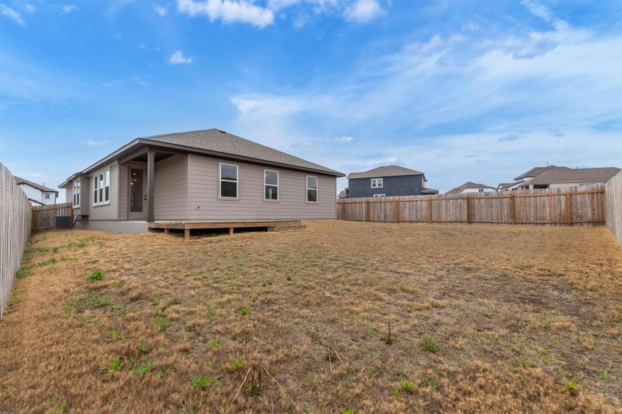 A spacious yard provides ample room for outdoor activities, bordered by a privacy fence.