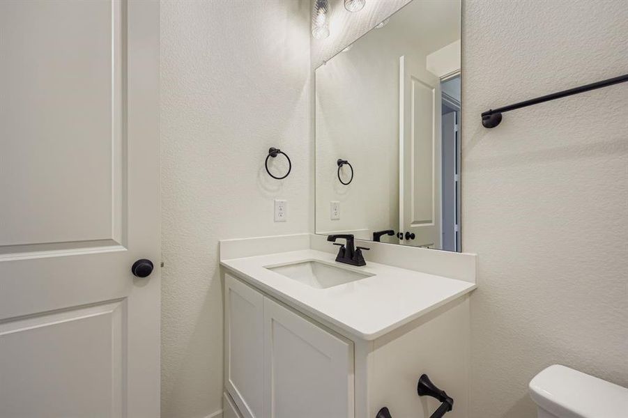 Half bathroom featuring a textured wall and vanity Half bathroom featuring a textured wall and vanity