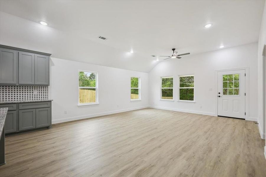 Unfurnished living room with light wood-type flooring, recessed lighting, vaulted ceiling, and ceiling fan Unfurnished living room with light wood-type flooring, recessed lighting, vaulted ceiling, and ceiling fan
