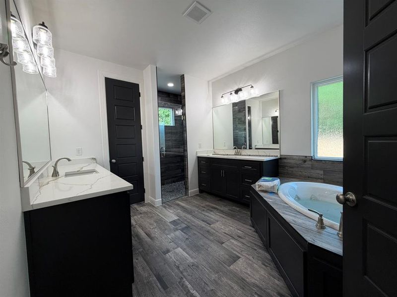 Spacious bathroom featuring wood-finish flooring and dark cabinetry